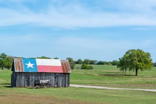 Weathered Texas barn with the Texas flag painted on its roof